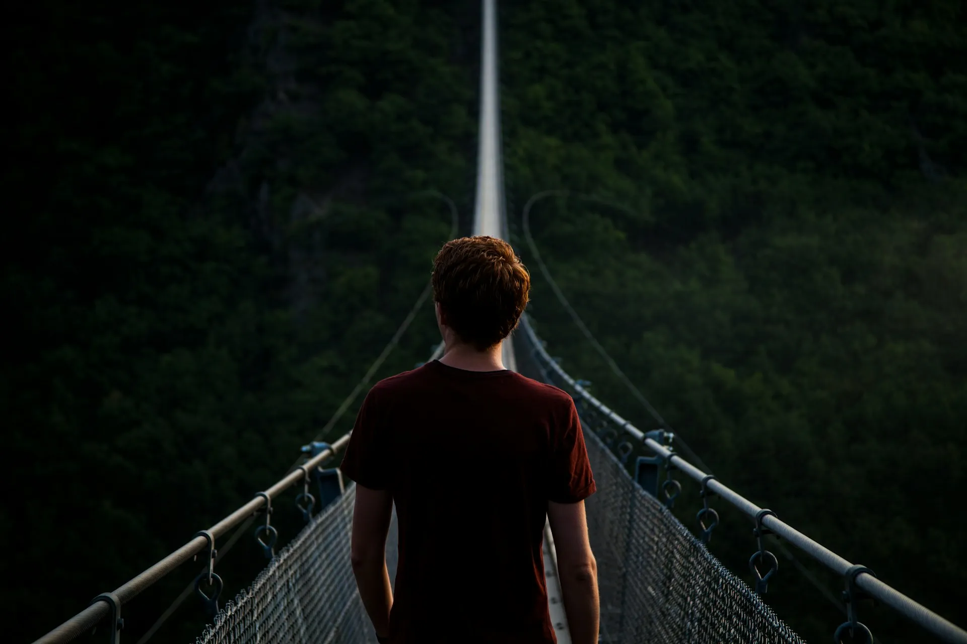 Man standing alone on hanging bridge